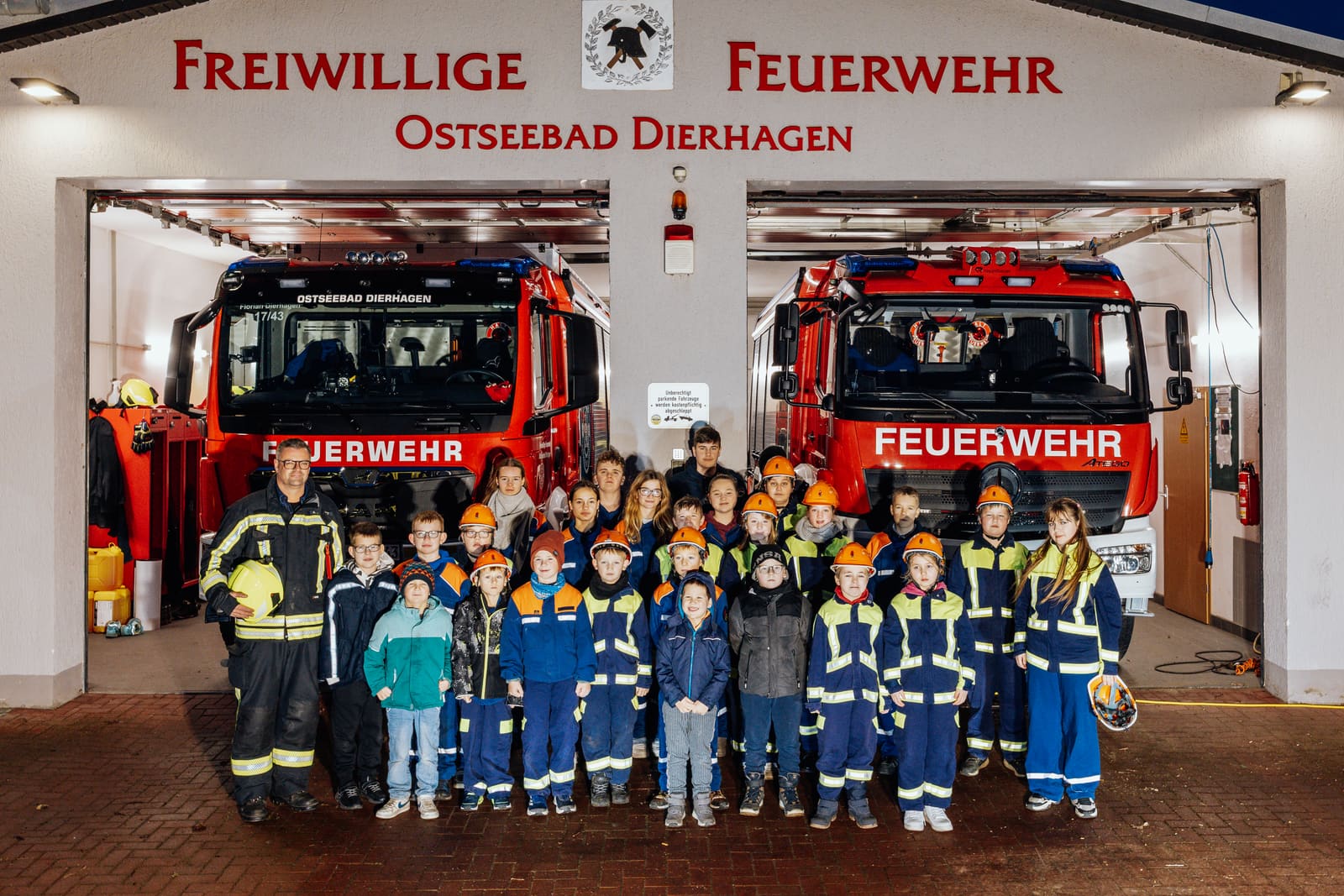 Die Kinder- und Jugendfeuerwehr Ostseebad Dierhagen mit ihren Betreuern vor dem Gerätehaus, zwischen HLF 20 und LF 20